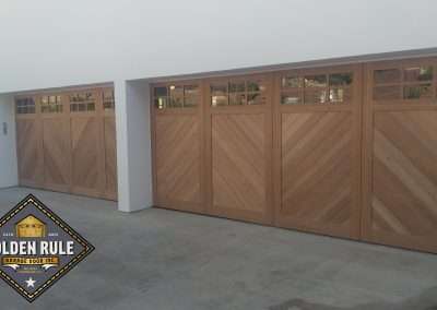 New Custom Wood Carriage House Garage Doors installed in San Juan Capistrano CA by Golden Rule Garage Door Inc. Chevron Pattern Stain-Grade Mahogany