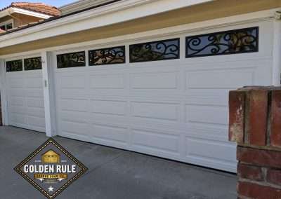 These non-insulated Unique Traditional Long Panel New Garage Doors in White with The Orleans windows were installed in San Juan Capistrano CA by Golden Rule Garage Door Inc.