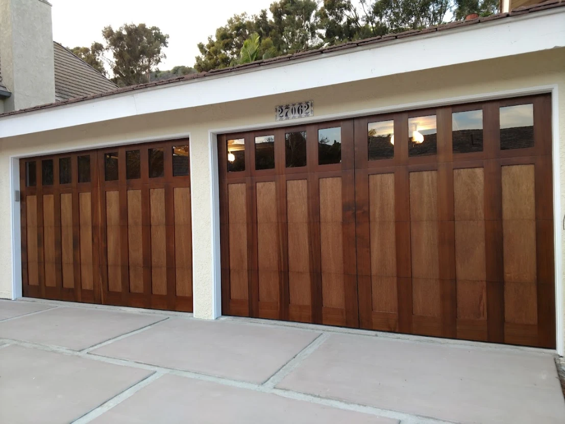 Two rich wood-finish garage doors with vertical plank design and a row of small square windows across the top of each door.
