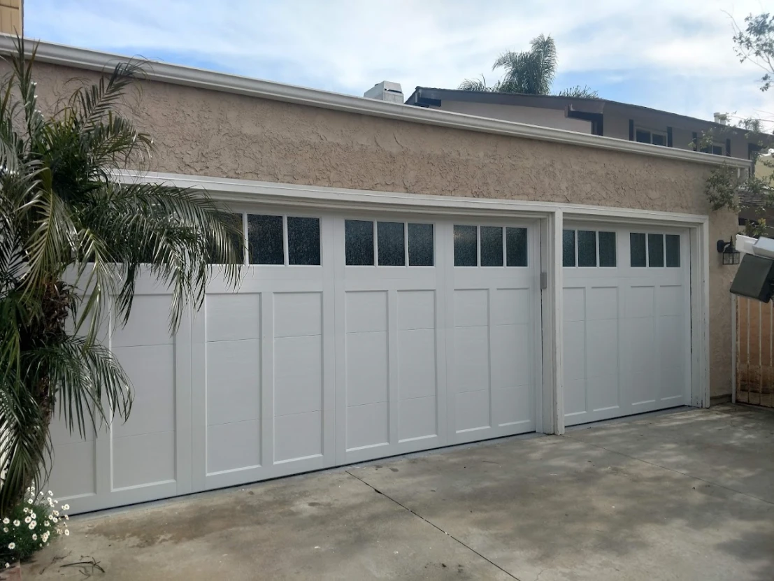 Two rich wood-finish garage doors with vertical plank design and a row of small square windows across the top of each door.