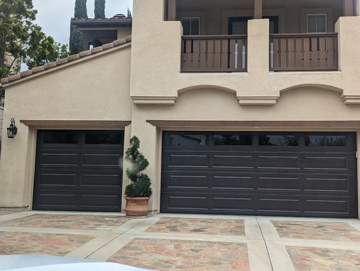 Two-story home with a black garage door and paved driveway entrance