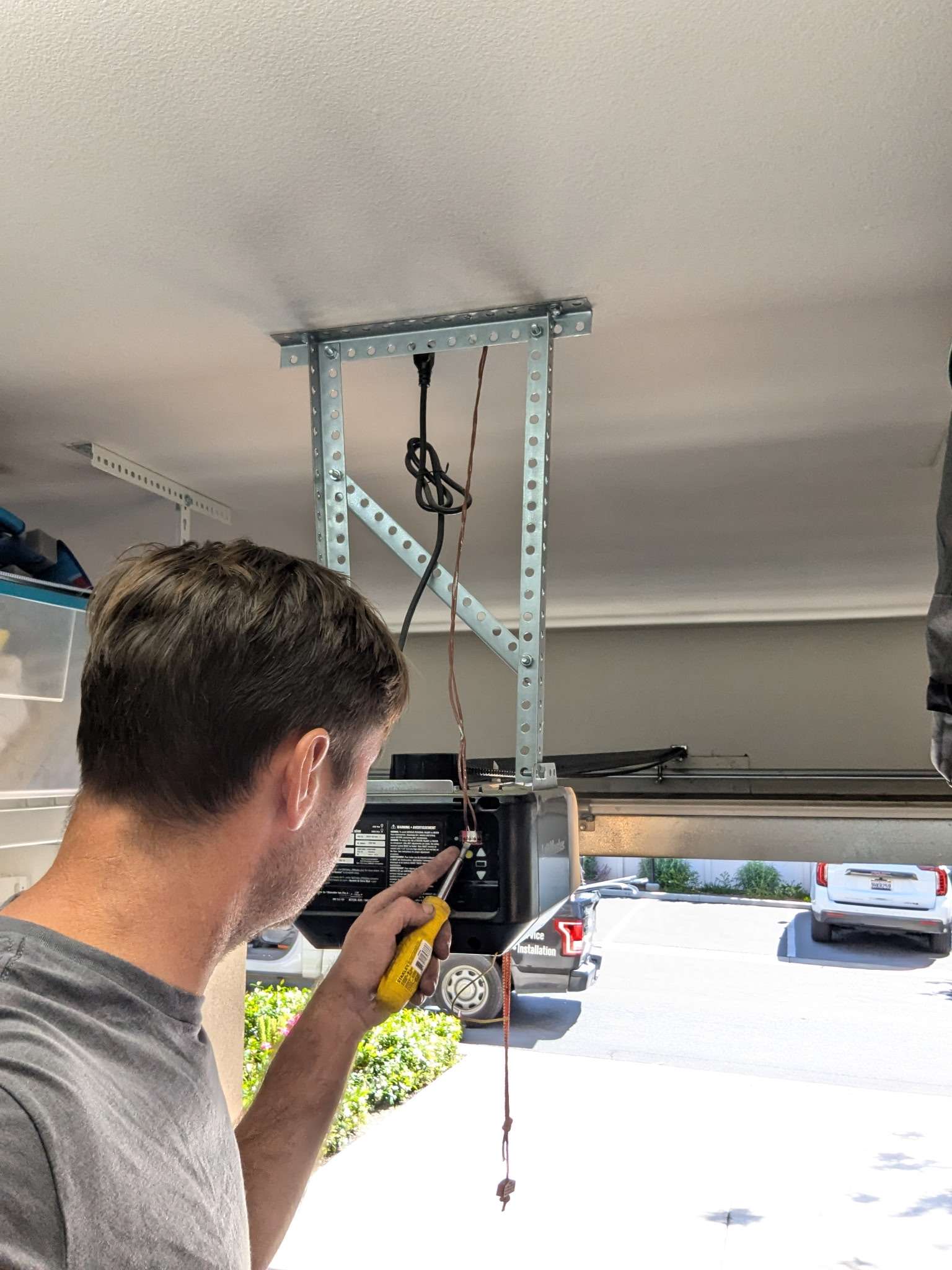 Technician repairing a garage door opener inside a residential garage