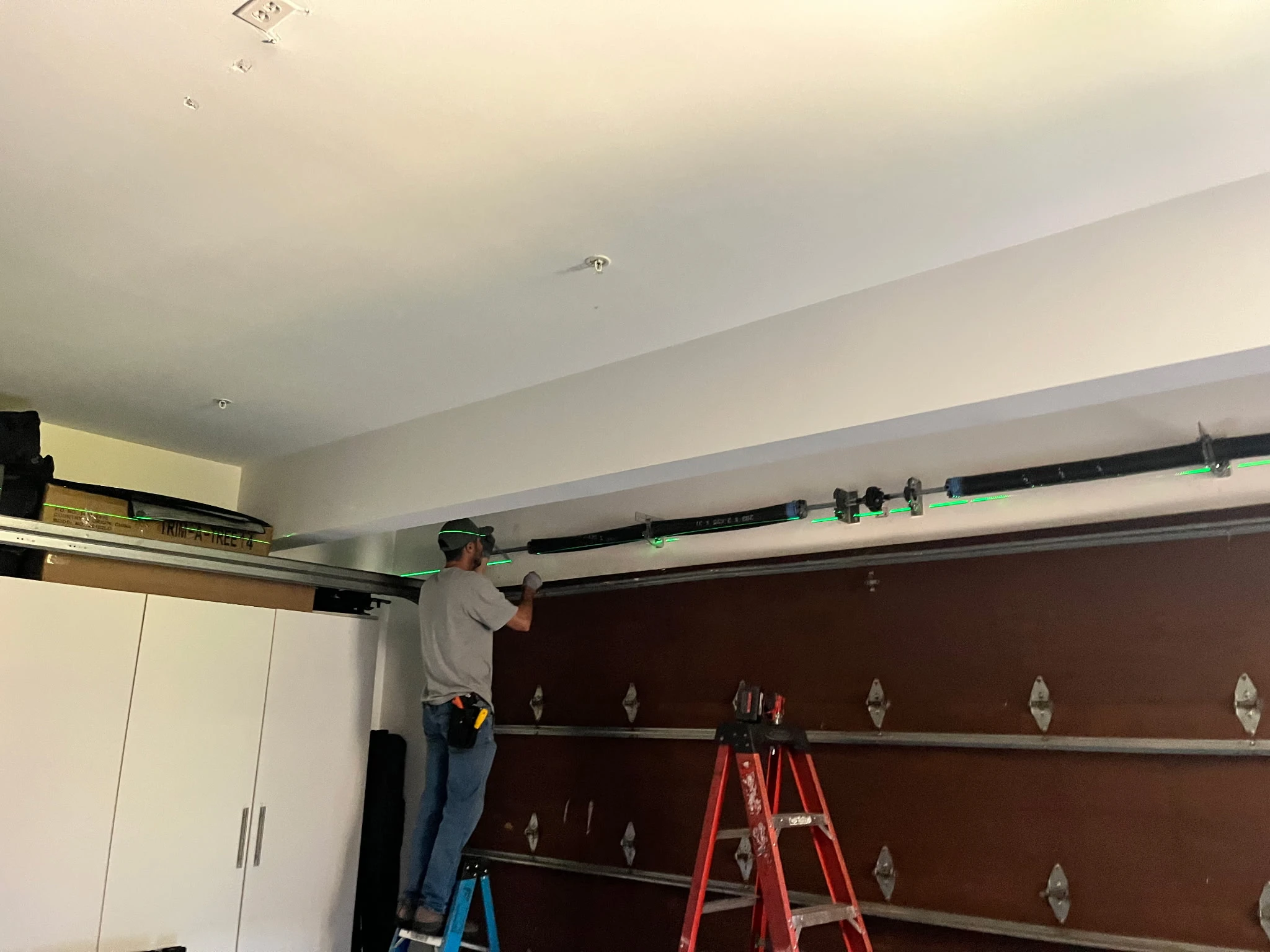 Golden Rule Garage Door Inc. technician working on overhead garage door components above a closed door in Orange County, CA